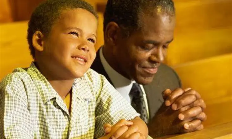 Warisan Iman Kristen Ayah dan anak laki-laki berdoa di gereja