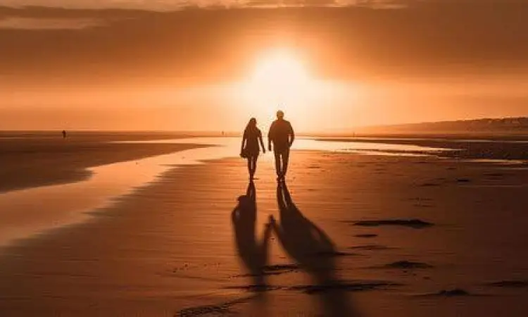 Pasangan berjalan di pantai melambangkan kebebasan dalam cinta
